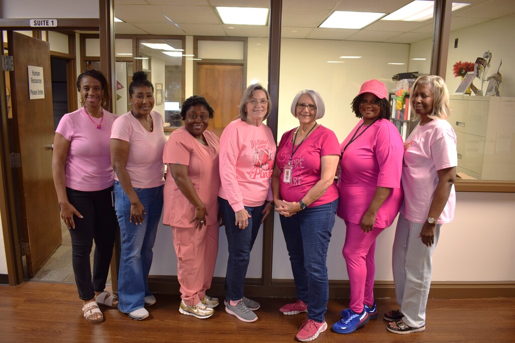 Seven Pulaski County Special School District employees stand together outside the Human Resources office wearing pink attire for Breast Cancer Awareness Month.
