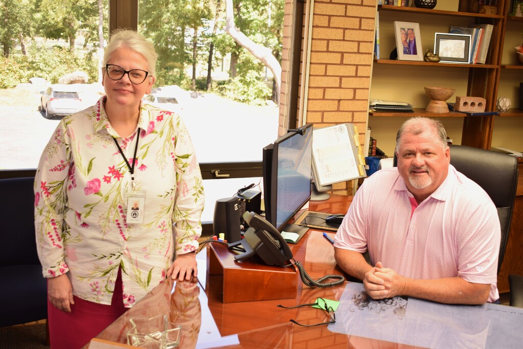 Two Pulaski County Special School District employees wearing pink pose in an office during Breast Cancer Awareness Month.