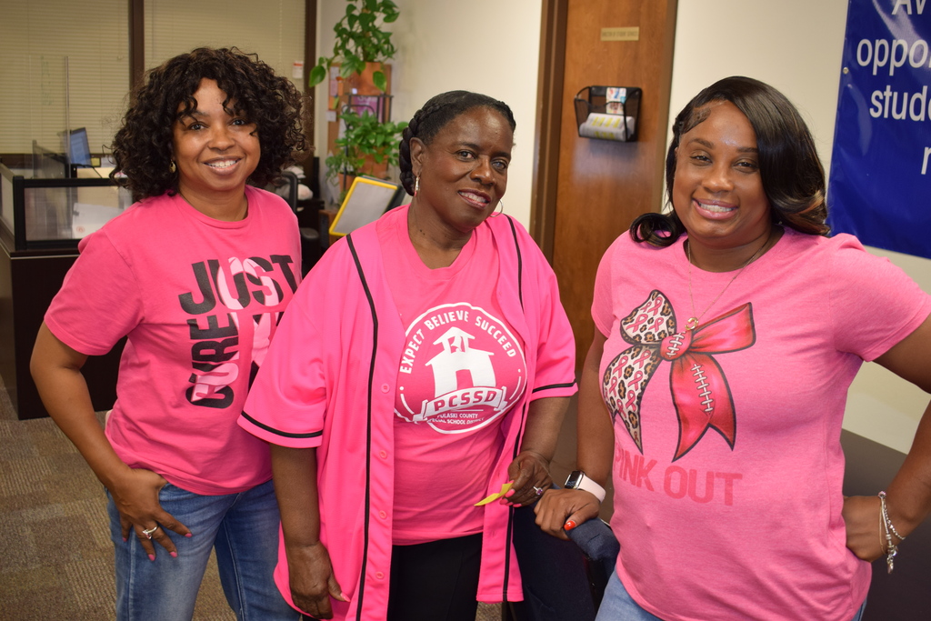 Three Pulaski County Special School District employees pose together wearing bright pink shirts in support of Breast Cancer Awareness Month.
