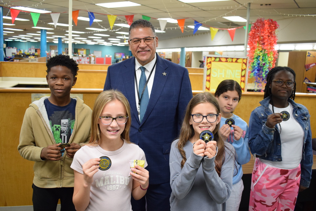 Sheriff Eric Higgins standing with students holding badge fidgets