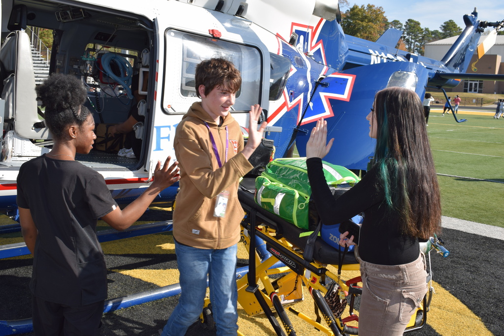 Students giving high fives after touring a helicopter