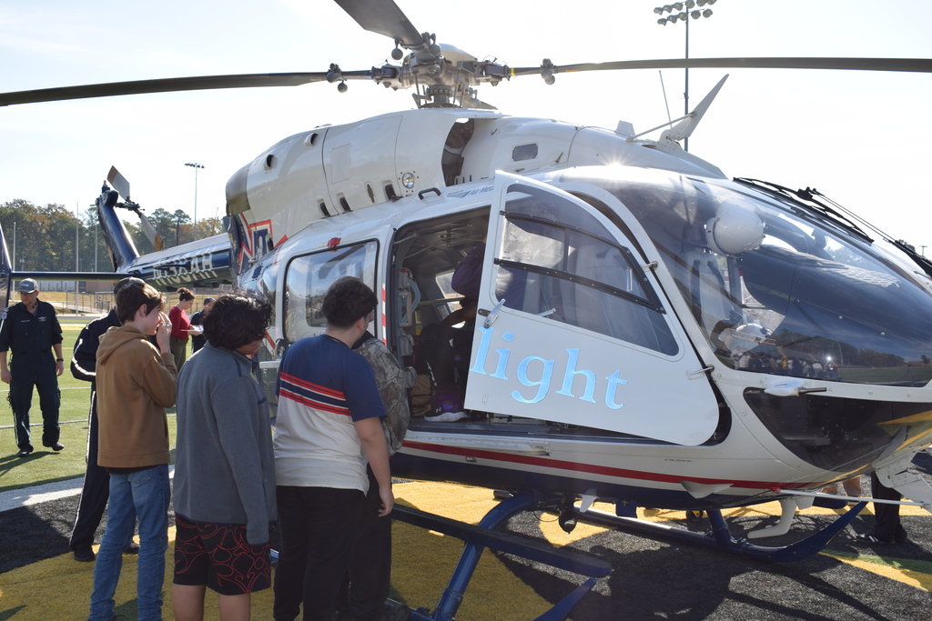 Students tour helicopter in a football field