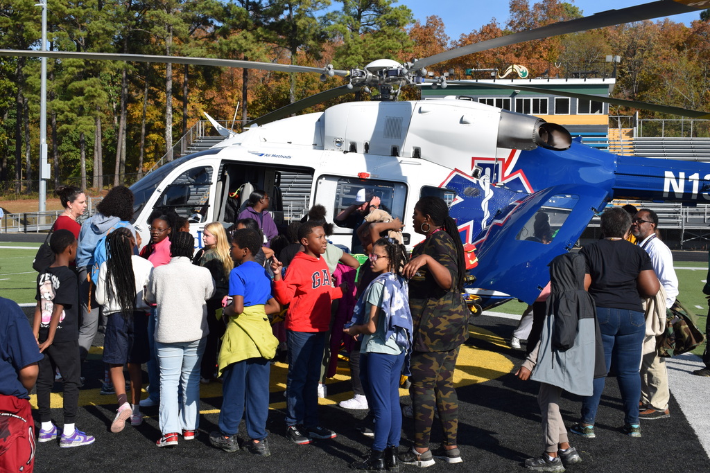Students stand in front of a helicopter