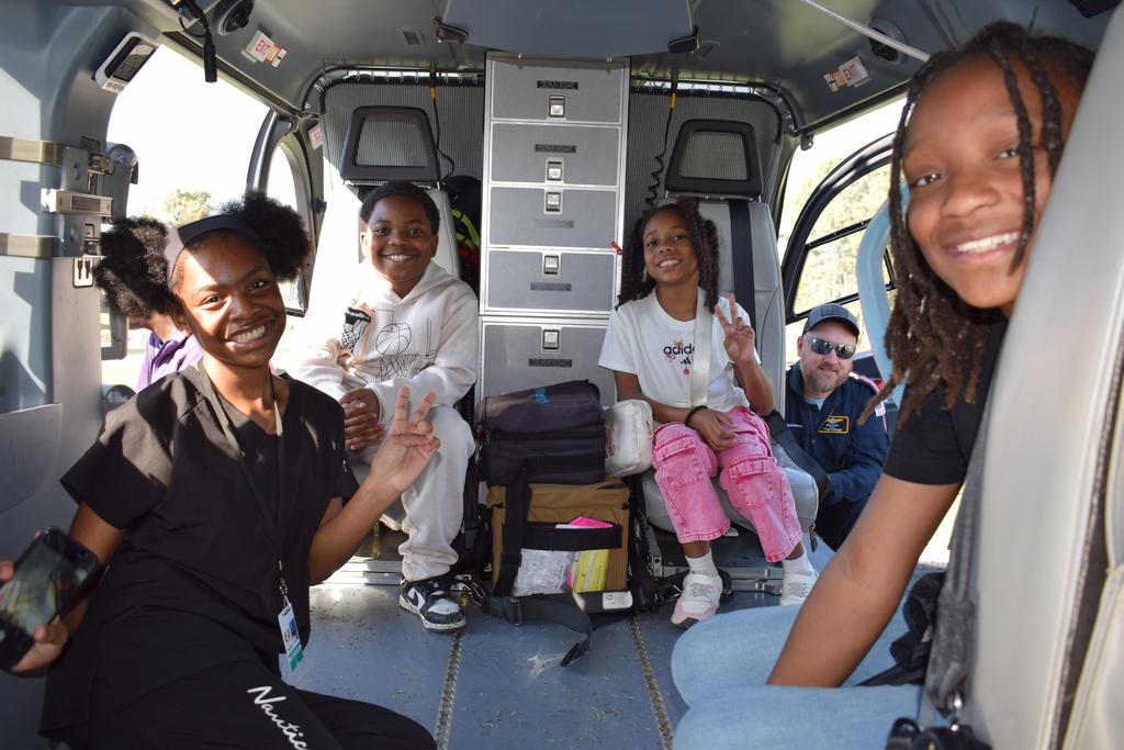 Four students and a pilot smile from within a helicopter