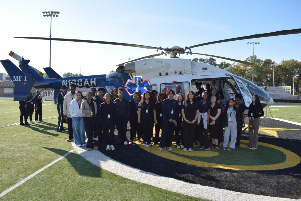 Students pose for a picture in front of a helicopter