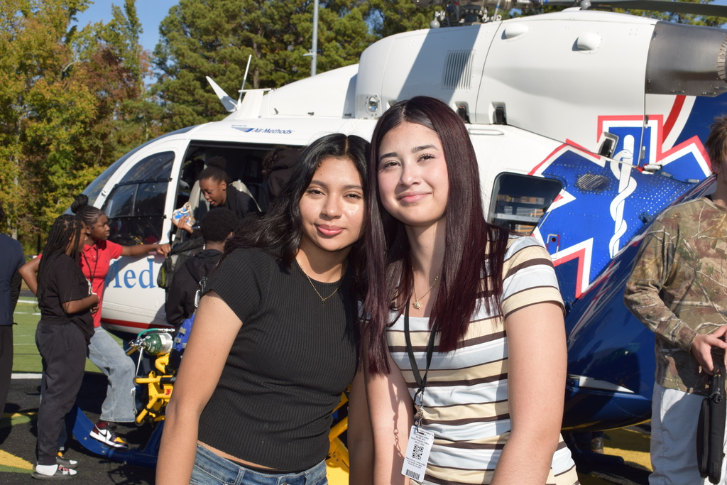 Students smile in front of a helicopter
