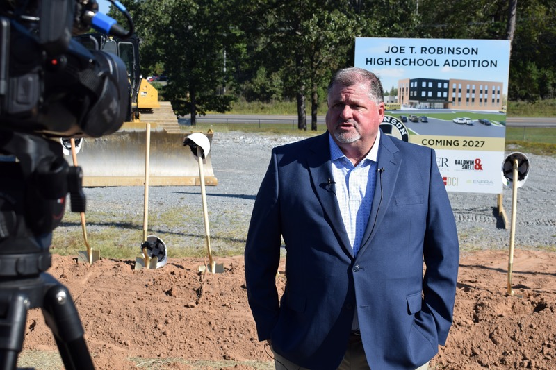 Superintendent Jeff Senn speaks to media in front of the Joe T. Robinson High School expansion sign that says "coming 2027"