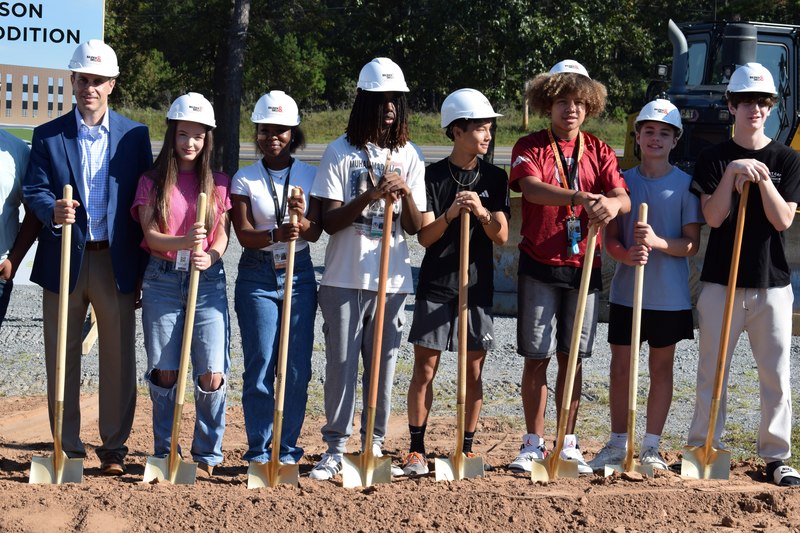 Joe T. Robinson High School students side by side with golden shovels smiling for a picture with Baldwin & Shell hardhats on before a groundbreaking