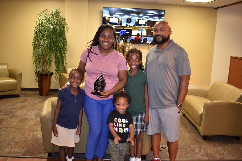 October 2025 Inspiration in Education winner Charde’ Wilson with her husband and three children smiling for a picture. She is holding her award.