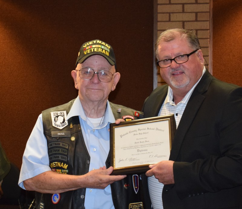 David Hoss dressed in his Vietnam Veteran clothers with Superintendent Senn. They are holding his diploma.