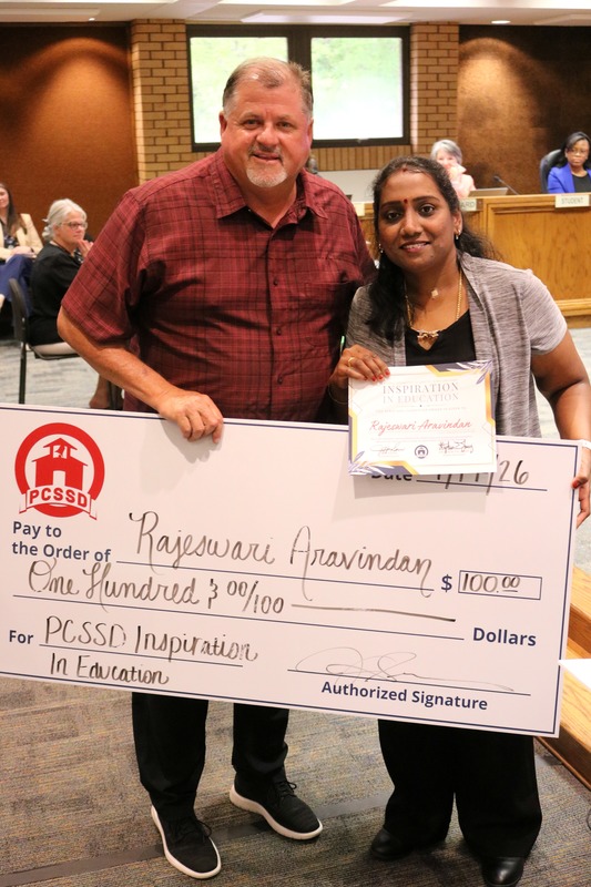 Jeff Sen and a teacher hold a check and inspiration in education award