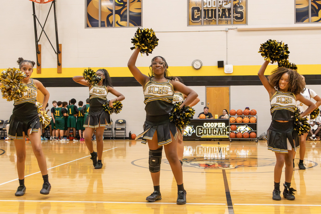 Four cheerleaders in uniform on gym court