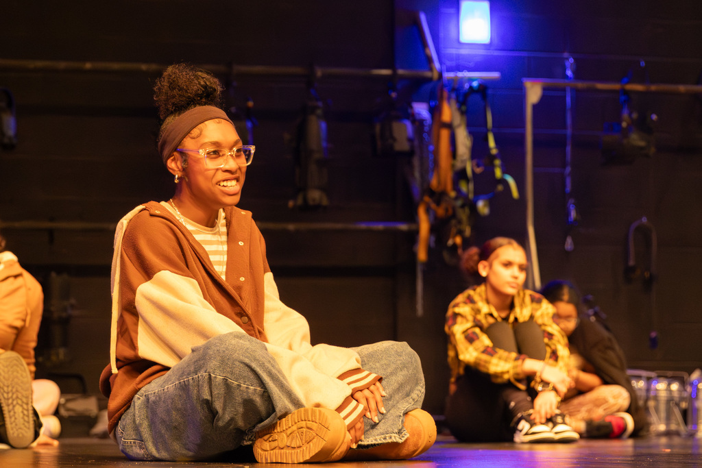 One student seated on a stage, smiling and attentive