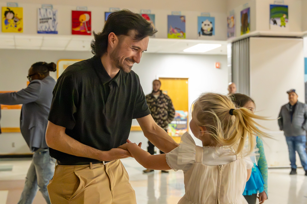 A man holding hands with a child, dancing in a circle