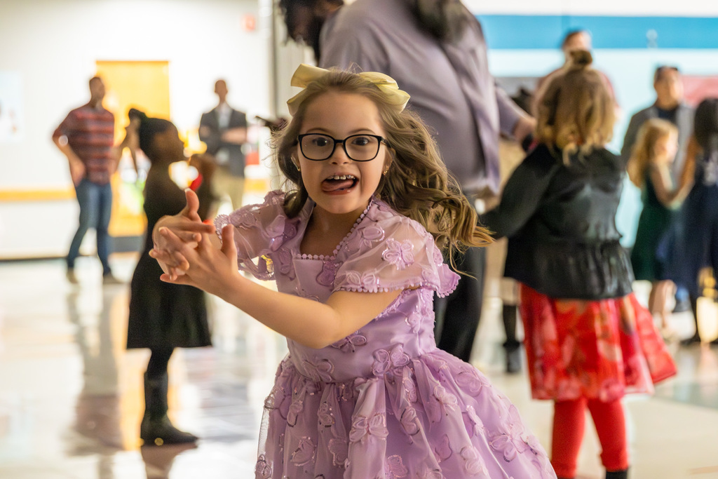 A girl in a pink dress spinning in a circle on the dance floor