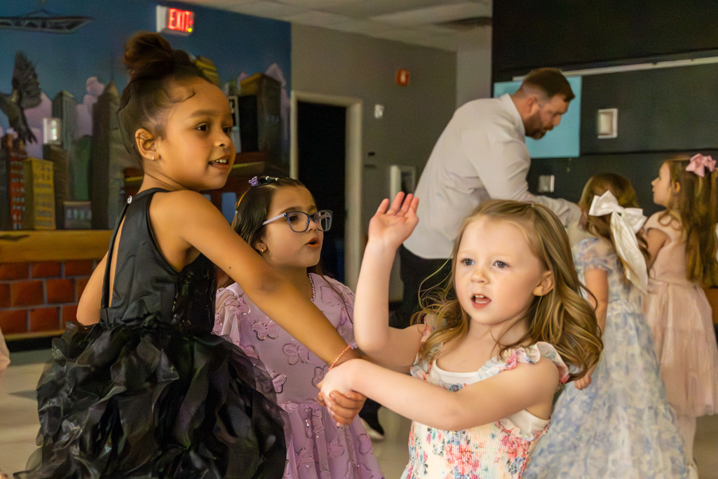 Three girls in a dance circle, holding hands and singing