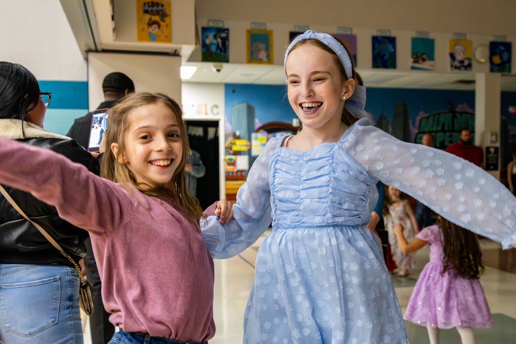 Two girls with their arms up in the air dancing