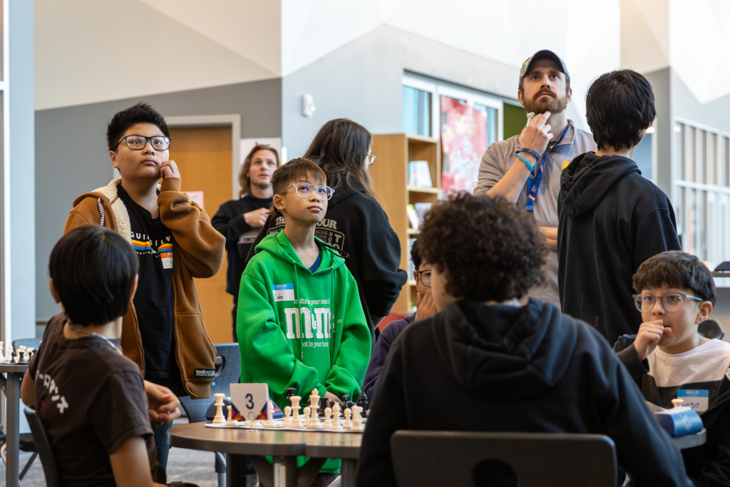 Students gathered around a chess board