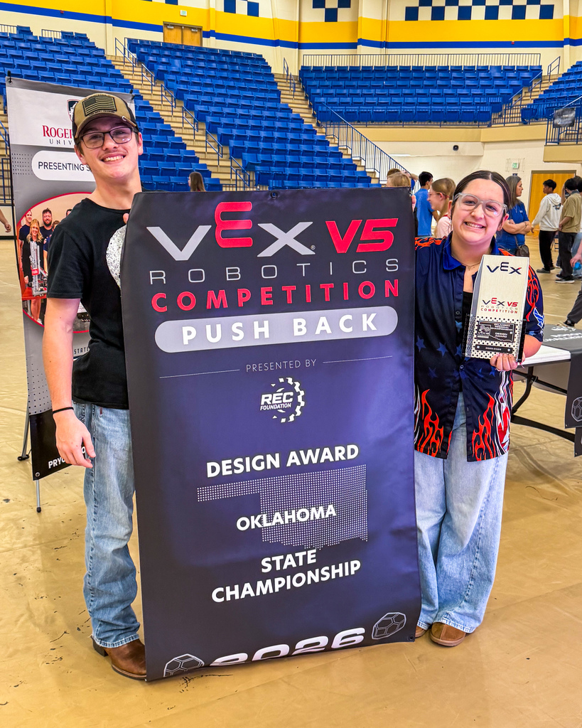 Two students posing with a championship banner and trophy