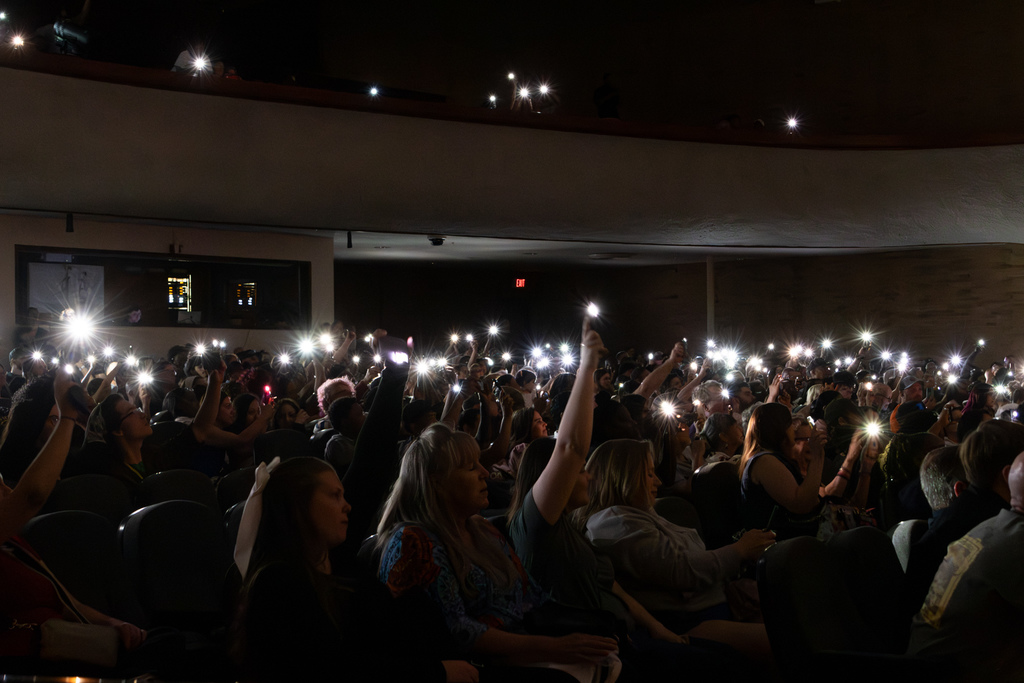audience members holding up cell phones with flashlights on