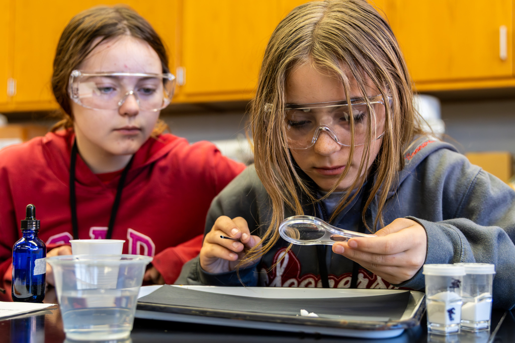 student viewing a powder through a magnifying glass