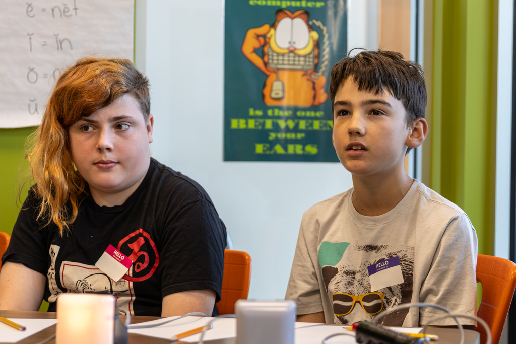 Two students sit at a quiz bowl table, watching and listening attentively as the round continues.