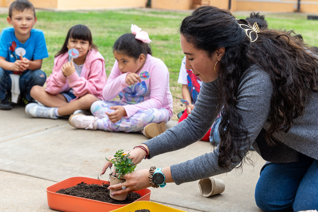 teacher demonstrates planting a flower to class