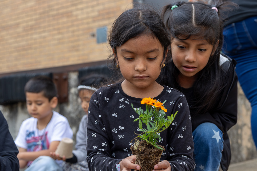 two girls pot a plant