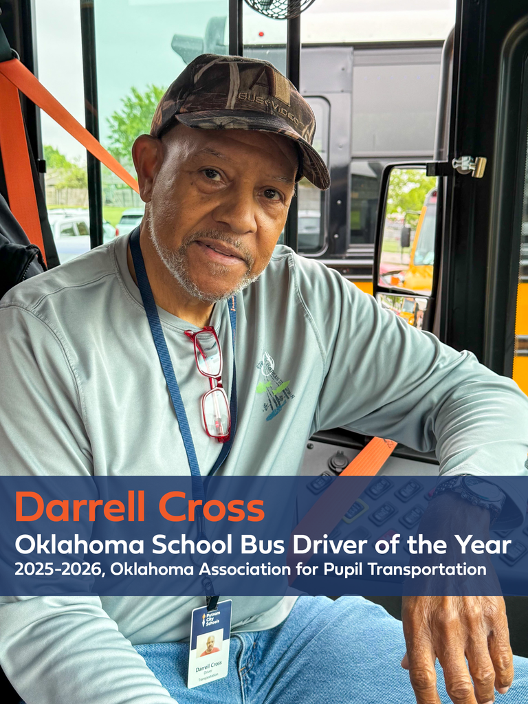 Portrait of Darrell Cross seated in the driver’s seat of a school bus, wearing a cap, long-sleeve shirt, and district ID badge, with a seatbelt visible across his shoulder. Text overlay reads: “Darrell Cross — Oklahoma School Bus Driver of the Year, 2025–2026, Oklahoma Association for Pupil Transportation.”