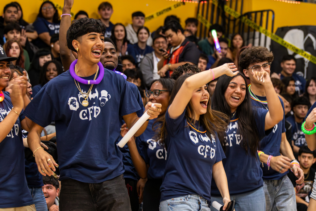 Students in matching CFD shirts cheer and wave glow sticks, celebrating during the fundraising event.