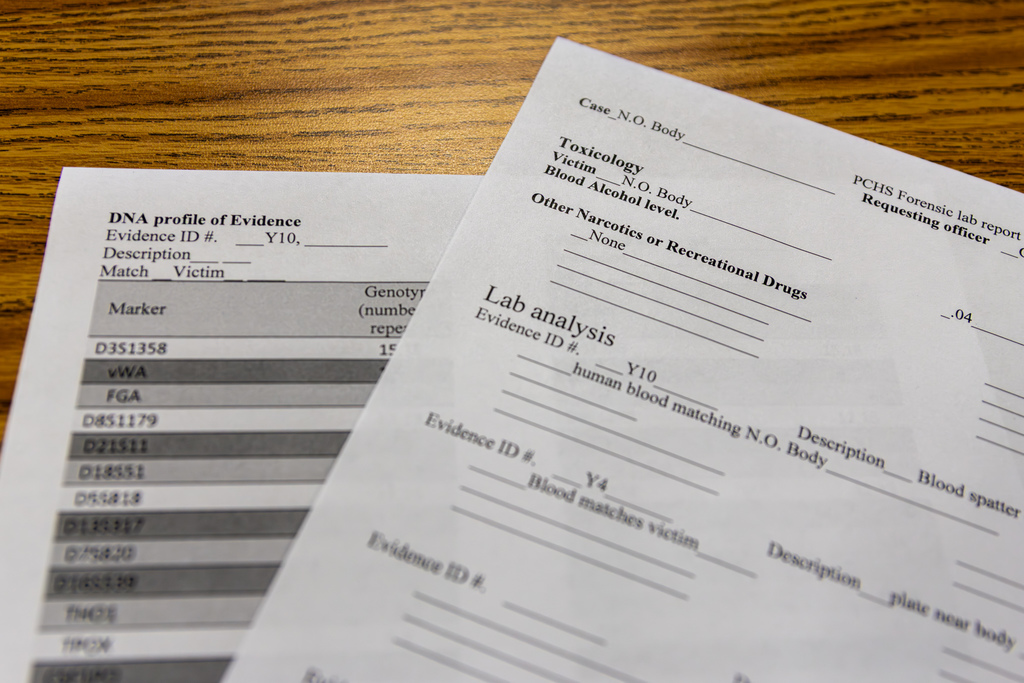 Printed forensic lab reports and DNA profile sheets laid out on a table, documenting evidence and analysis results.