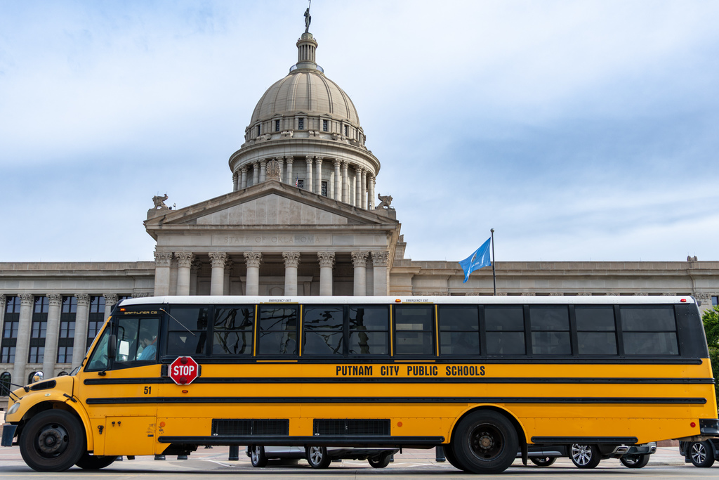Putnam City Public Schools bus parked in front of the Oklahoma State Capitol building.