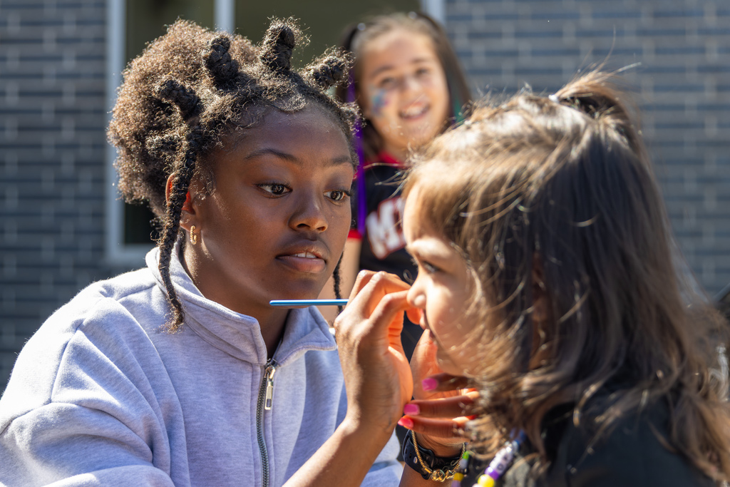 A student paints another student’s face during an outdoor activity at the Putnam City Arts Festival.