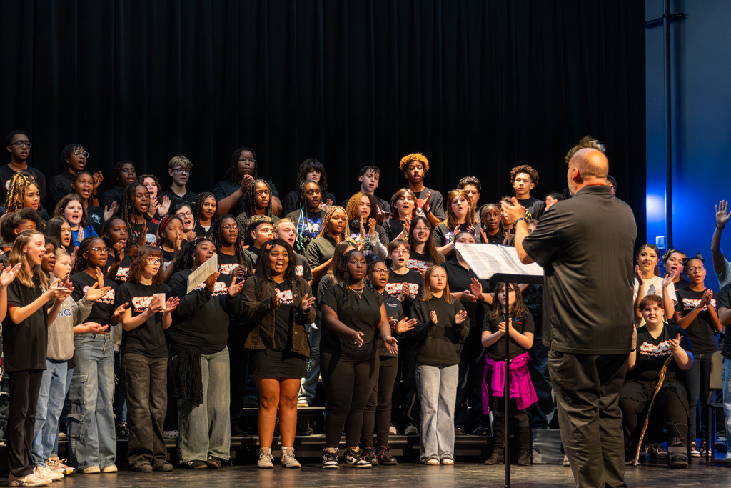 A student choir performs on stage during the Putnam City Arts Festival as the director conducts from the front.