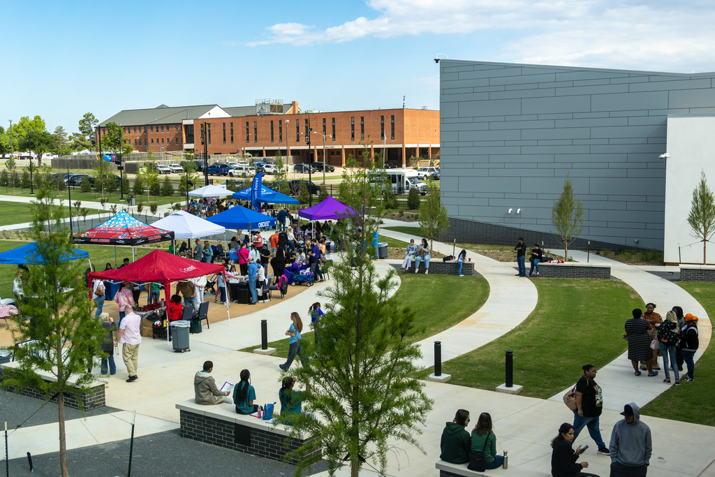 A wide outdoor view of the Putnam City Arts Festival shows vendor tents, visitors, and families gathered outside the Centennial Center.