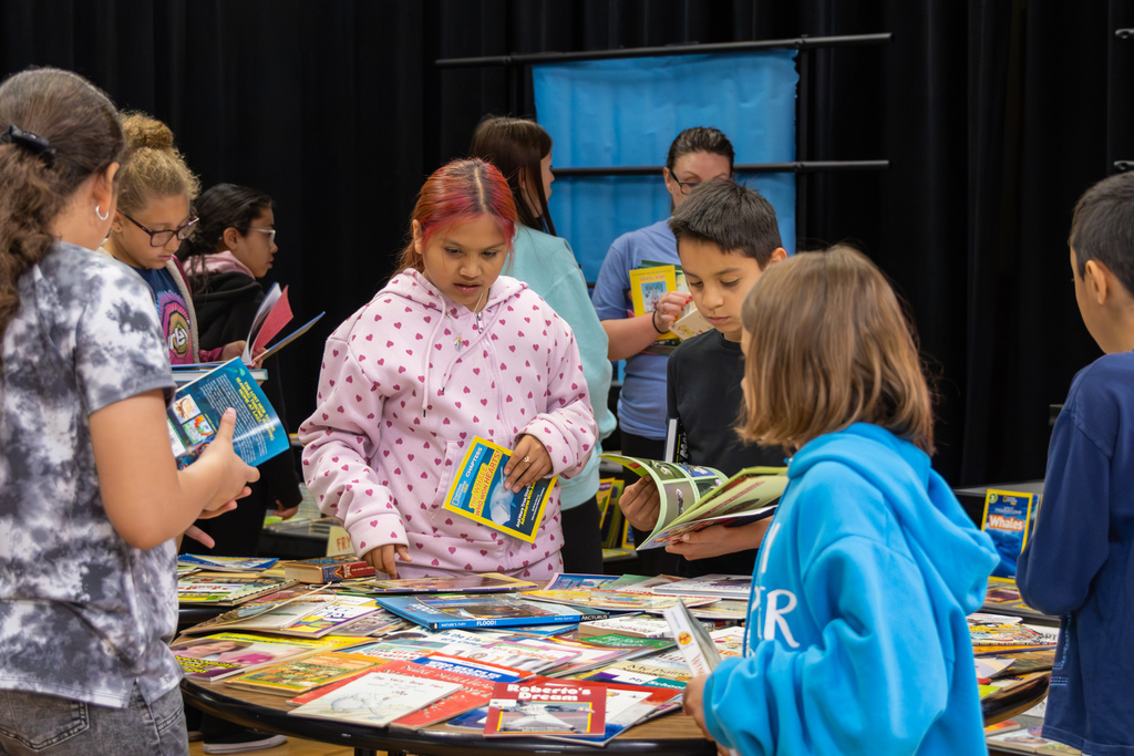 Overholser Elementary students browse a table full of books, choosing titles to take home from the Free Book Fair.