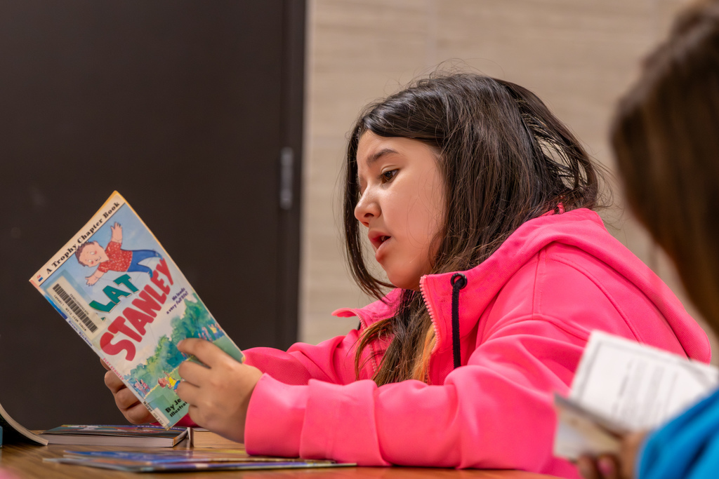 A student reads a Flat Stanley book while seated at a table during Overholser Elementary’s Free Book Fair.