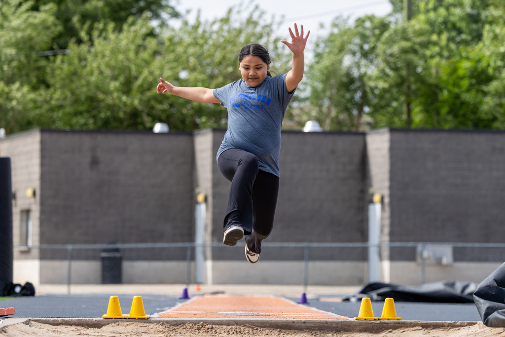 An Overholser Elementary student jumps into the sand pit during the long jump event.