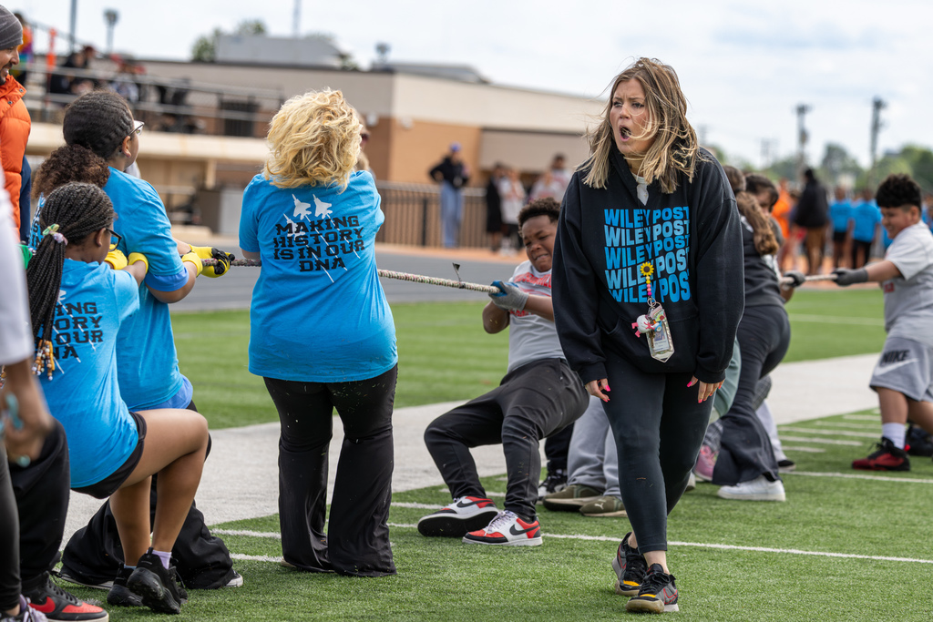 Wiley Post Elementary students compete in tug-of-war while a staff member cheers them on from the sideline.