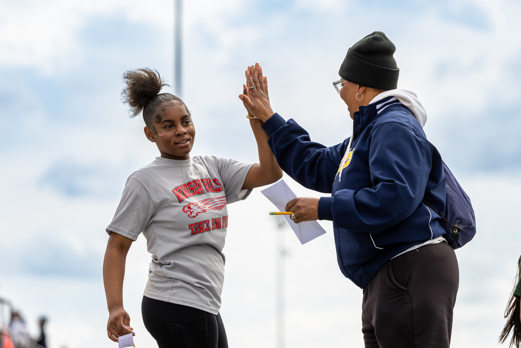 A Windsor Hills Elementary student high-fives an adult after competing at the elementary track meet.