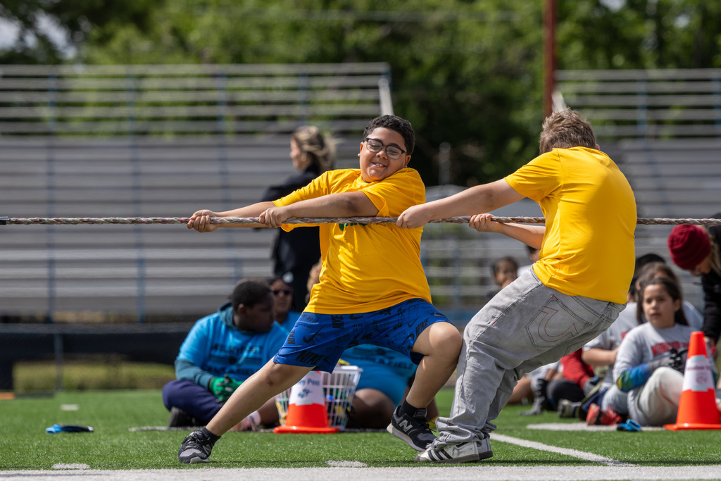 Two students in yellow shirts pull during a tug-of-war event at the elementary track meet.
