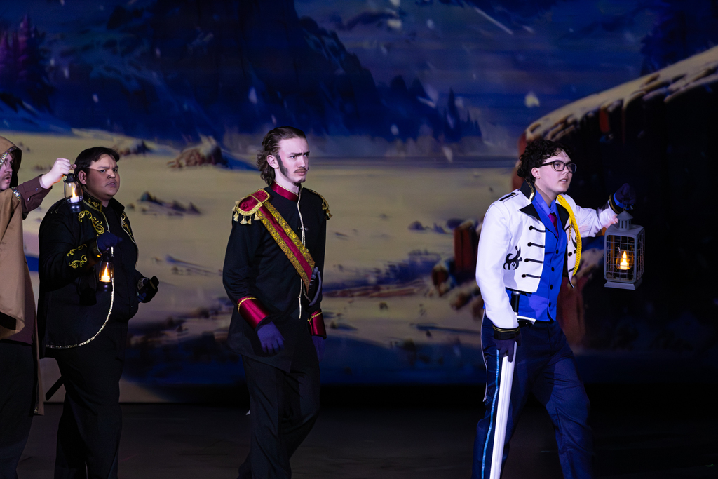 Putnam City North students perform a nighttime scene from Frozen: The Broadway Musical, walking across the stage with lanterns.