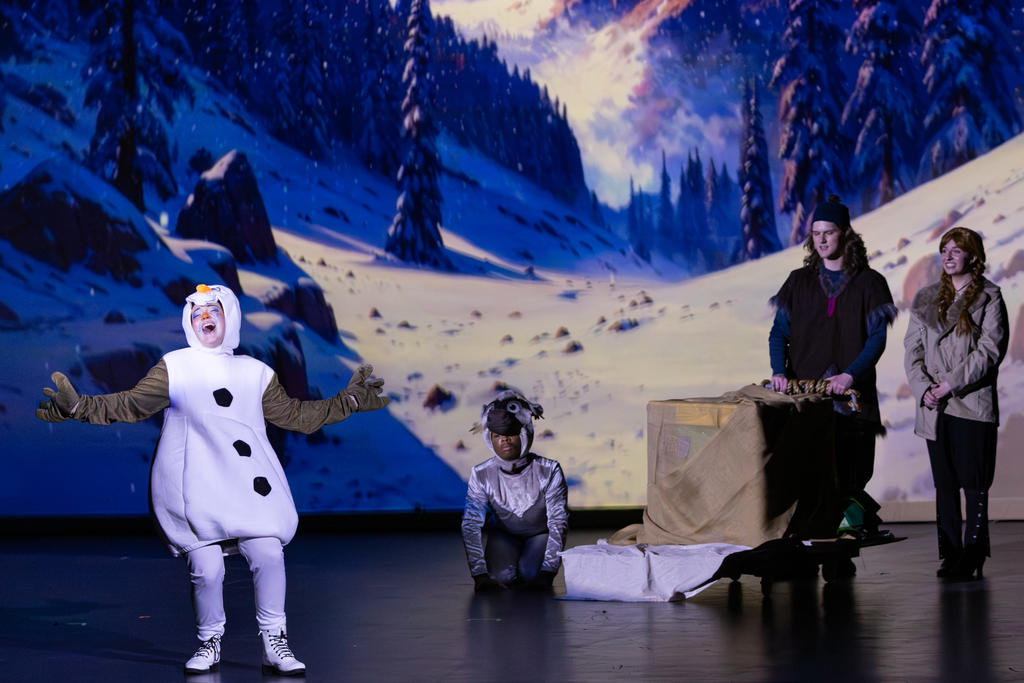 Putnam City North students perform a snowy scene from Frozen: The Broadway Musical, with students dressed as Olaf, Sven, Kristoff and Anna on stage.