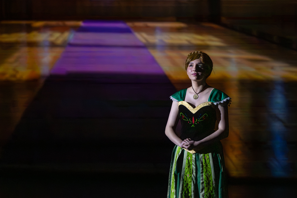 A Putnam City North student performs a solo moment as Anna in Frozen: The Broadway Musical, standing under dramatic stage lighting with a castle backdrop behind her.