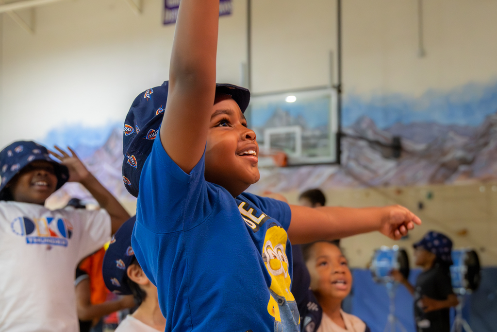 A Rollingwood Elementary student smiles and reaches upward while dancing during the Thunder Reading Challenge celebration.