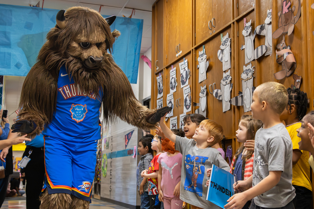 Oklahoma City Thunder mascot Rumble high-fives Rollingwood Elementary students lined up in the hallway during a celebration for the Thunder Reading Challenge.