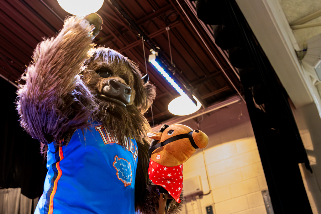 Oklahoma City Thunder mascot Rumble waves from the stage while holding a toy horse during Rollingwood Elementary’s Thunder Reading Challenge celebration.