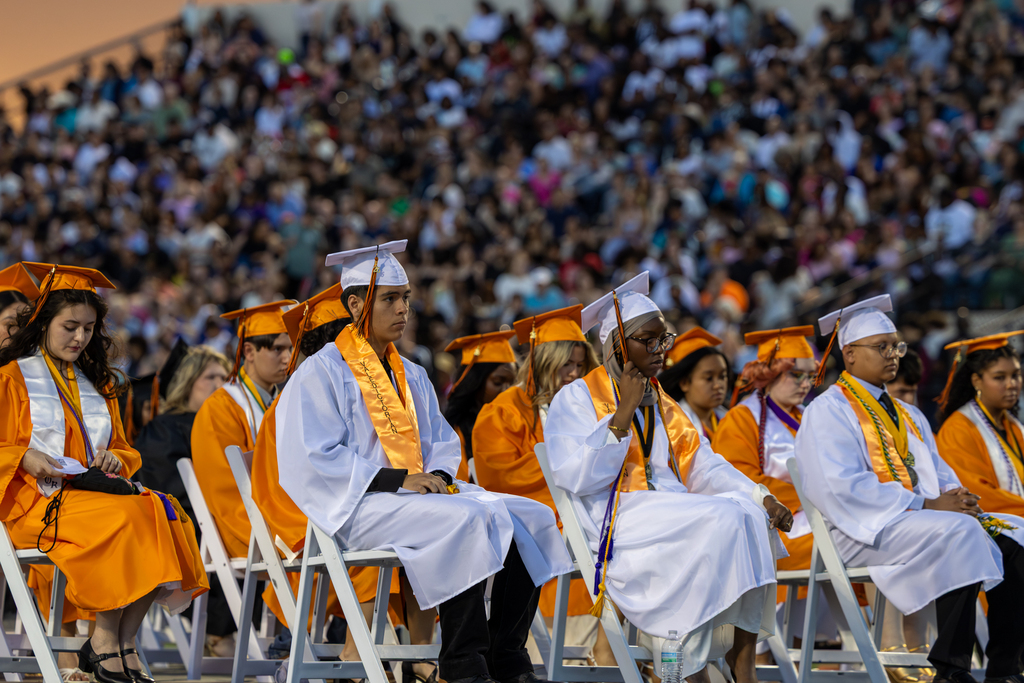 A wide group of students in graduation gowns seated during a graduation ceremony