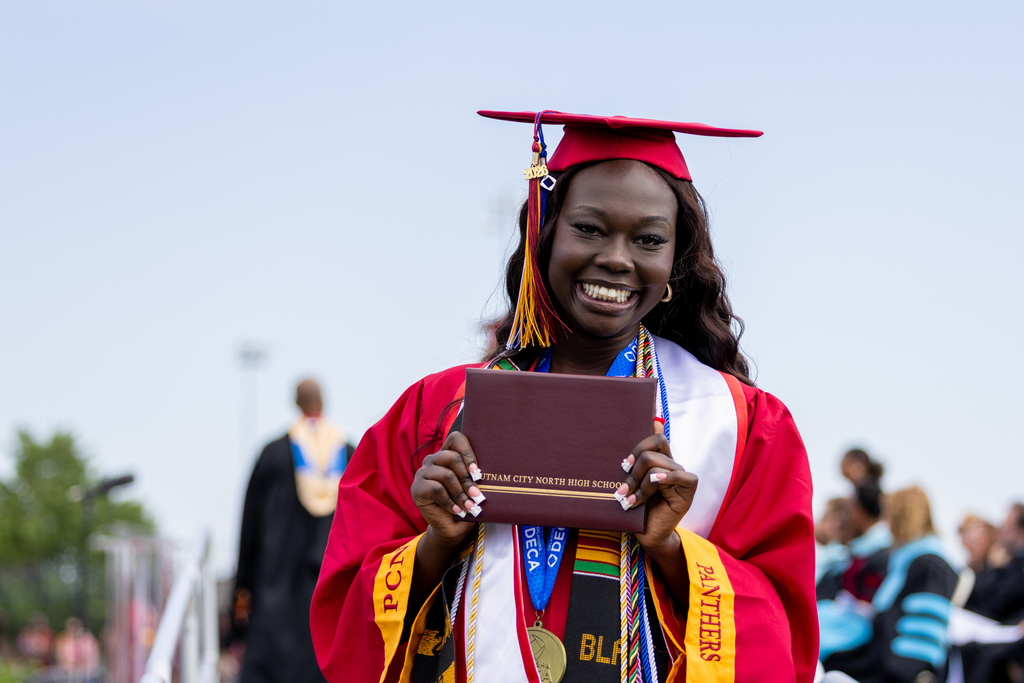 A Putnam City North graduate smiles while holding a diploma cover after the graduation ceremony.