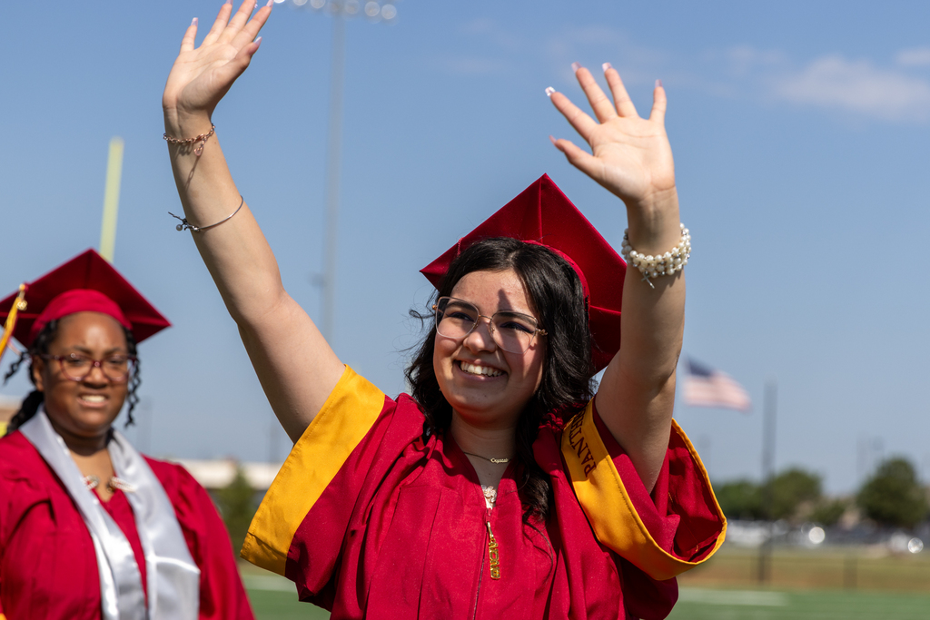 A Putnam City North graduate smiles and waves with both hands during the graduation ceremony.